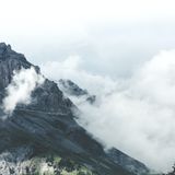 A dramatic mountain landscape partially obscured by clouds, creating a moody atmosphere.