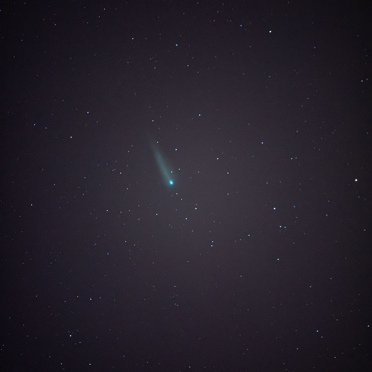 A night sky filled with stars, featuring a bright comet with a glowing tail at the top right.