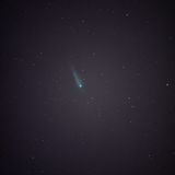 A night sky filled with stars, featuring a bright comet with a glowing tail at the top right.